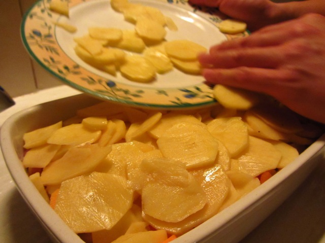 Antoni spreading potatoes across the top of the gratin